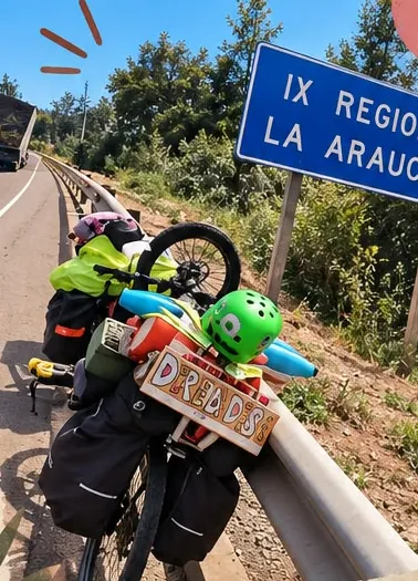 Bicicleta cargada con alforjas y un letrero de dreads junto al cartel de la IX Región de La Araucanía